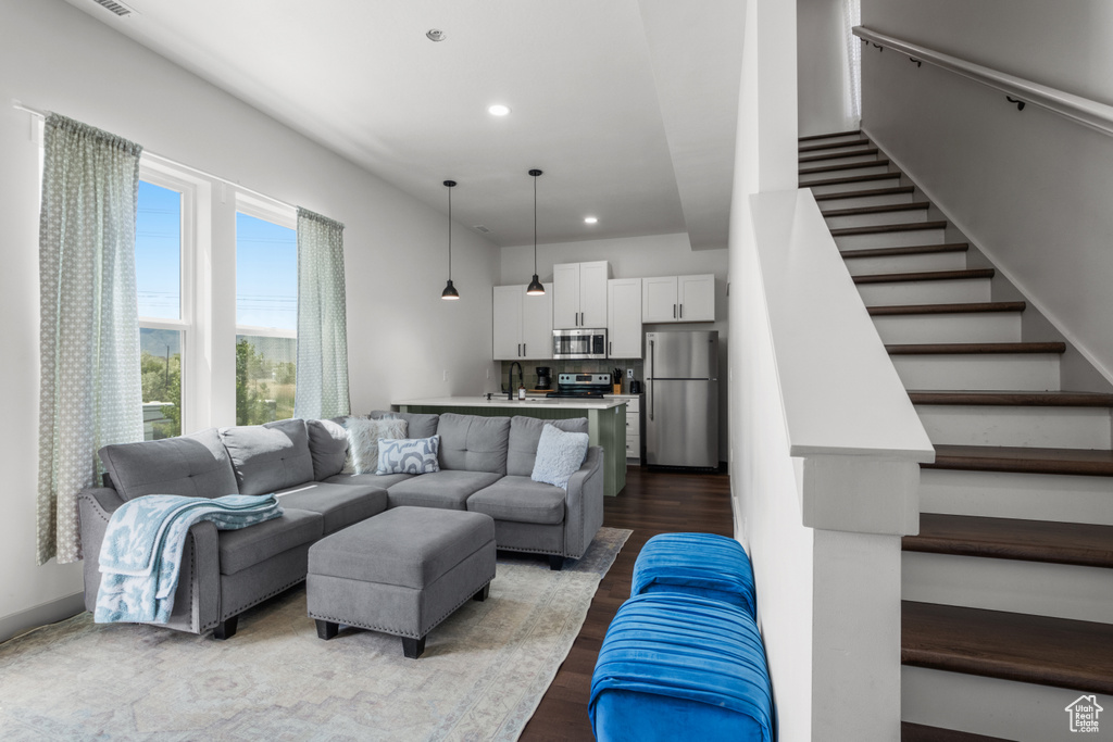 Living room with stairs, recessed lighting, and dark wood-style flooring