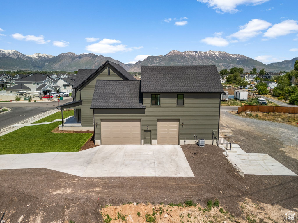 View of front of house featuring concrete driveway, an attached garage, a mountain view, roof with shingles, and a residential view