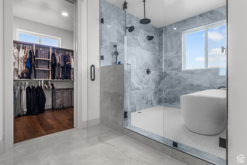 Bathroom featuring a stall shower, a freestanding bath, a spacious closet, and marble finish flooring