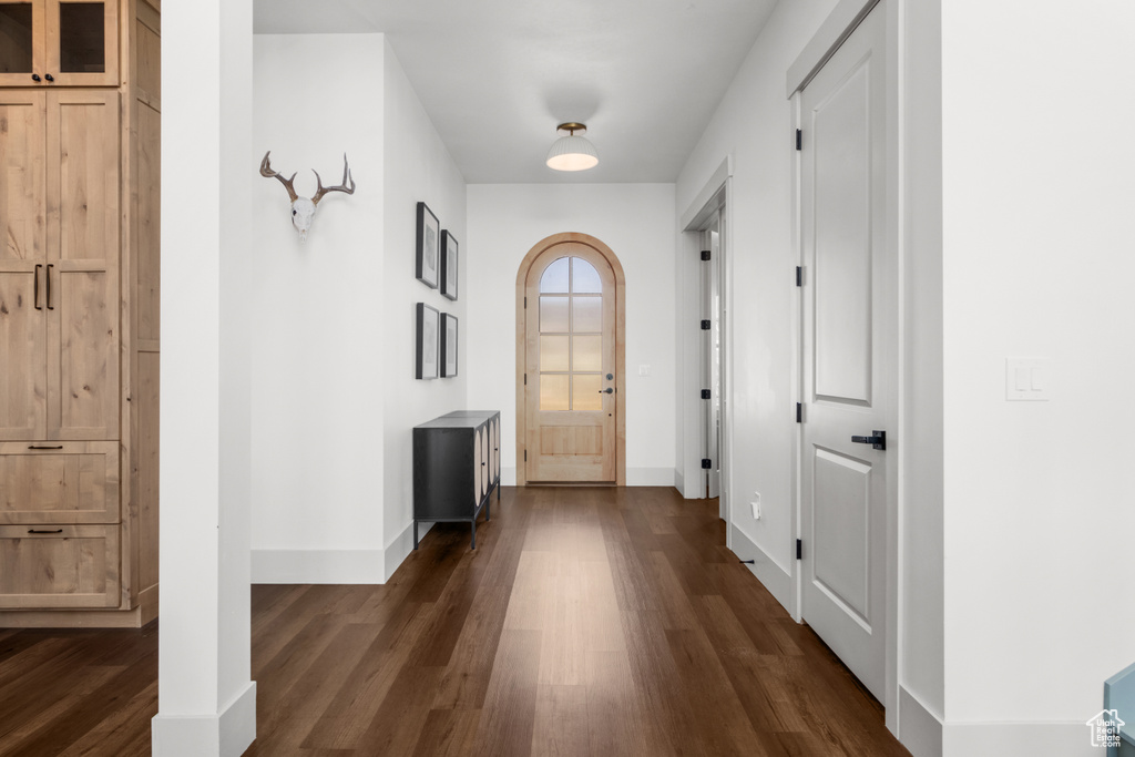 Doorway featuring dark wood-style floors and baseboards