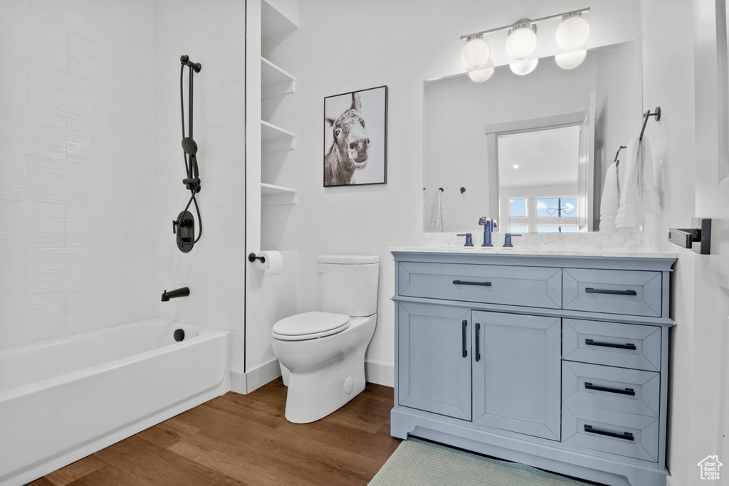 Bathroom featuring vanity, wood finished floors, toilet, and  shower combination