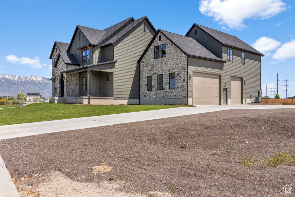 View of front facade with stone siding, a garage, driveway, board and batten siding, and a mountain view