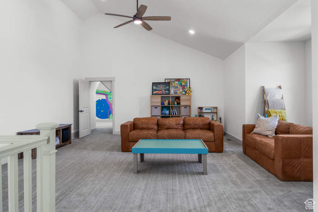 Living area featuring light colored carpet, a ceiling fan, and high vaulted ceiling