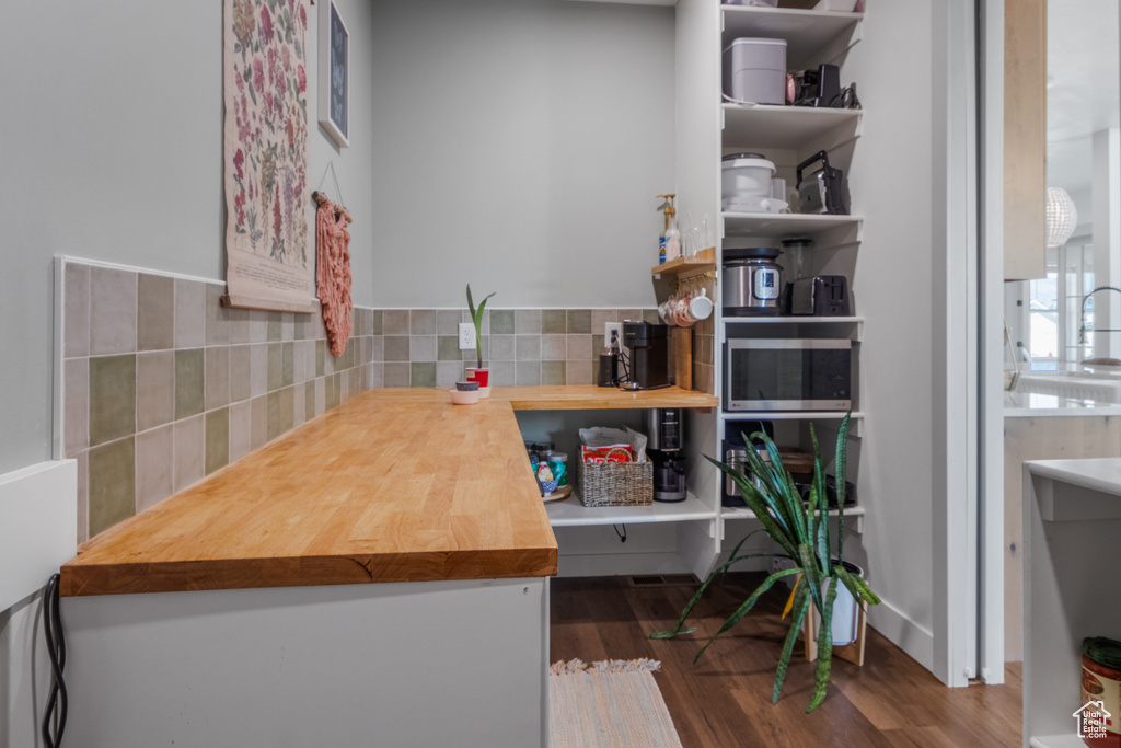 Kitchen featuring butcher block counters, backsplash, and wood finished floors