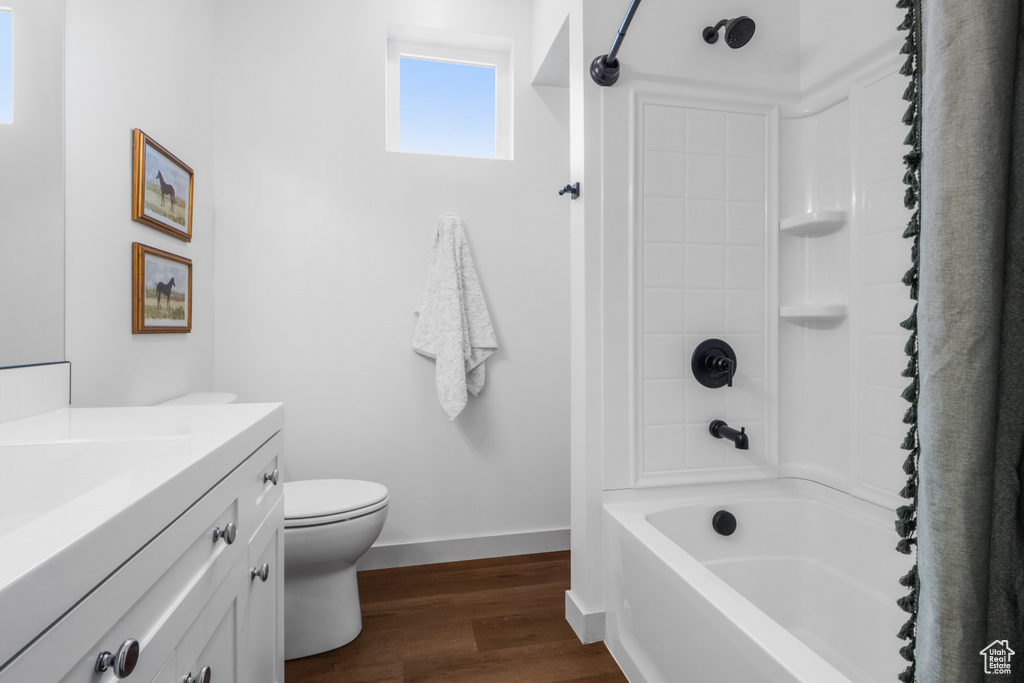 Bathroom with vanity, wood finished floors,  shower combination, toilet, and baseboards