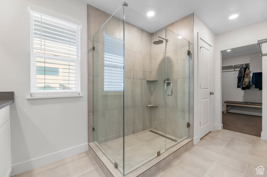 Bathroom featuring a stall shower, a walk in closet, baseboards, and recessed lighting