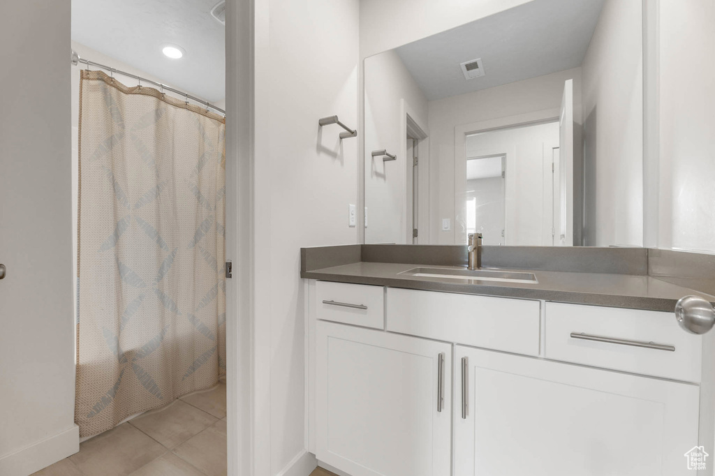 Bathroom with vanity, baseboards, tile patterned flooring, and a shower with shower curtain
