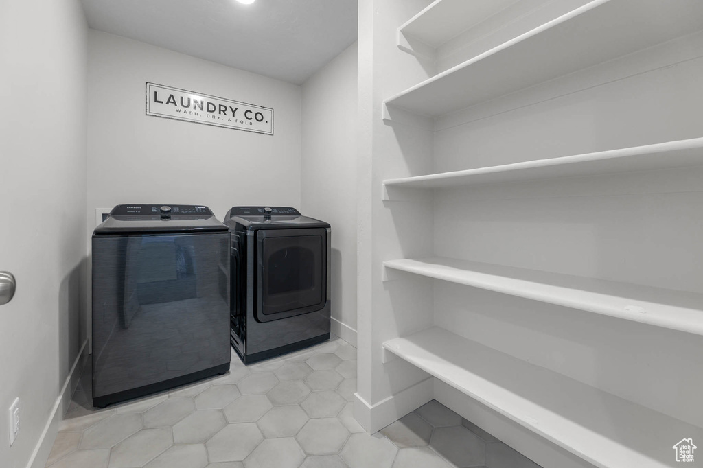 Laundry room with washer and clothes dryer, baseboards, and light tile patterned floors