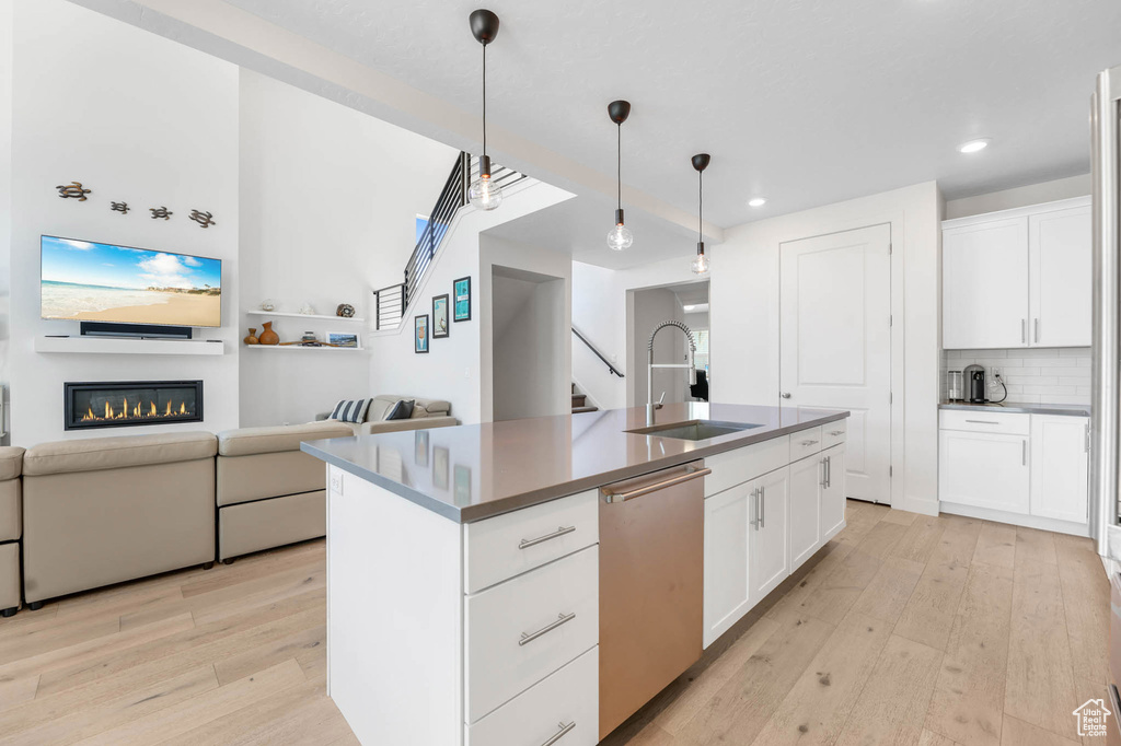Kitchen featuring a sink, dishwasher, light wood-style floors, open floor plan, and recessed lighting