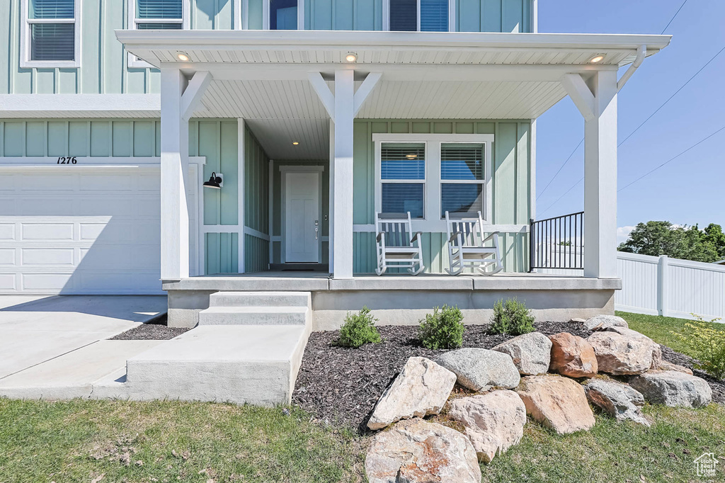 Property entrance with covered porch, board and batten siding, and a garage