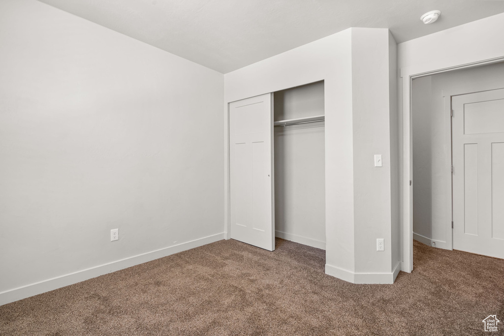 Unfurnished bedroom with carpet flooring, a closet, and baseboards