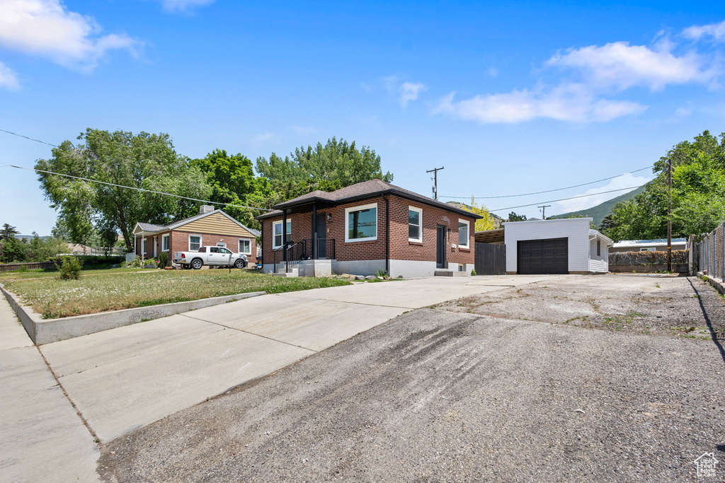 View of front of house featuring brick siding, an outbuilding, driveway, and a garage
