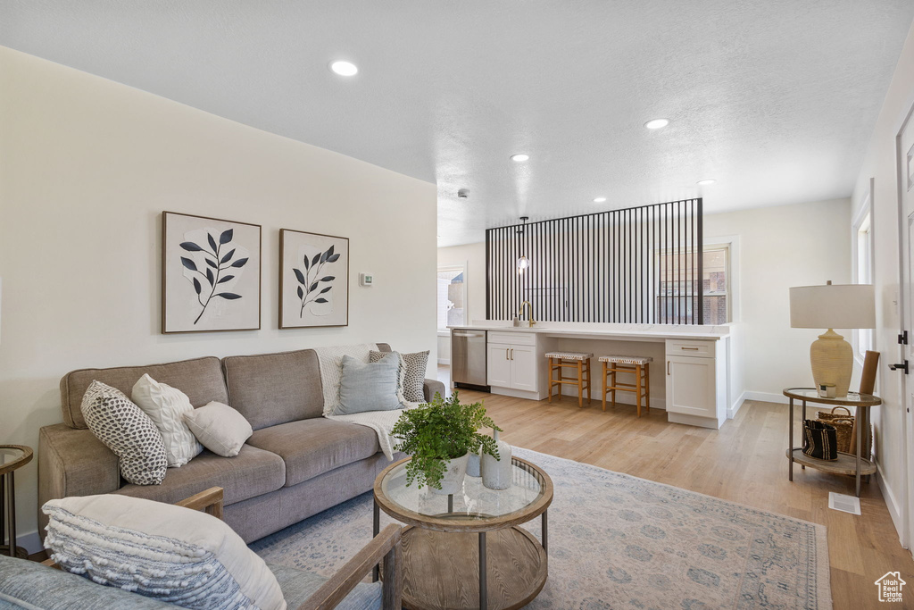 Living area with light wood finished floors and recessed lighting