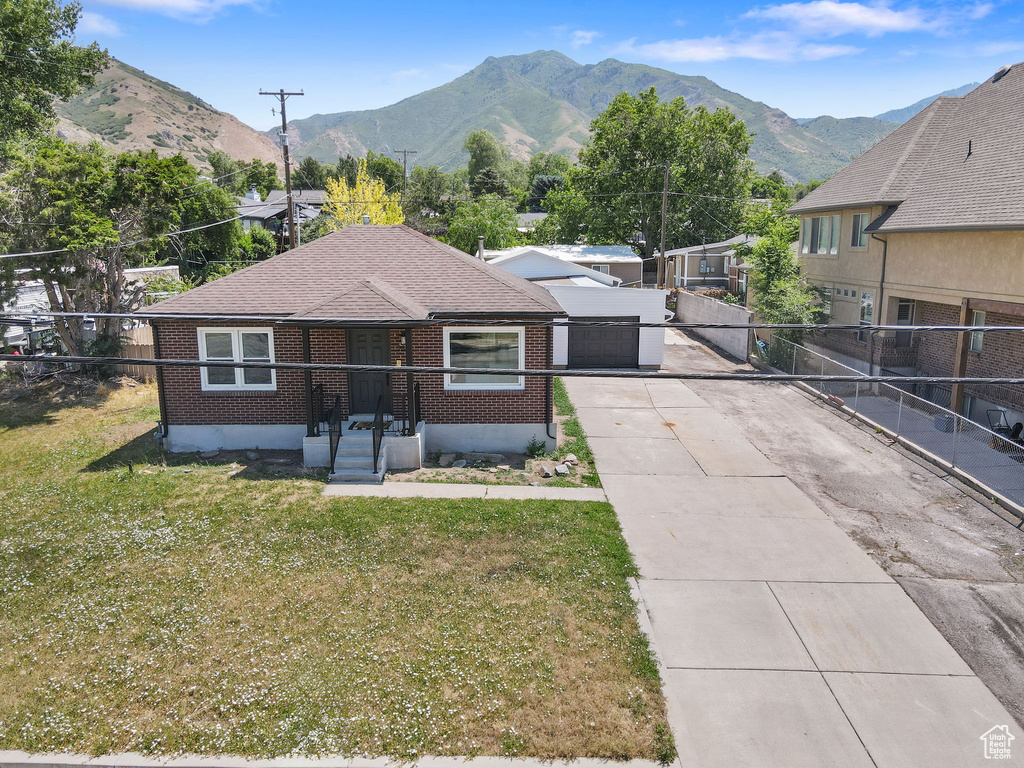 View of front of property featuring concrete driveway, brick siding, a mountain view, and a shingled roof