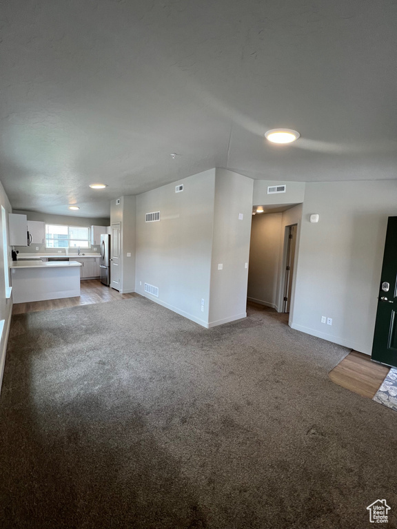 Unfurnished living room featuring carpet and baseboards