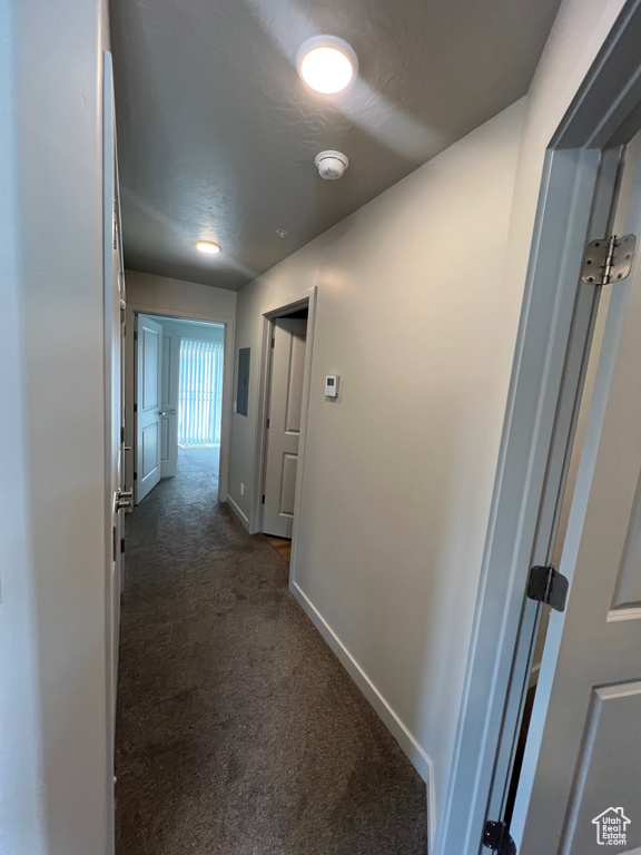 Hallway with dark colored carpet and baseboards