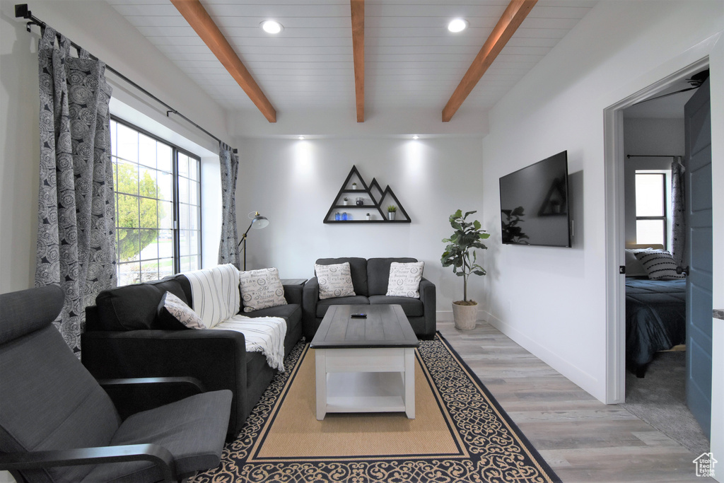 Living room with light wood finished floors, recessed lighting, and wood ceiling with exposed beams
