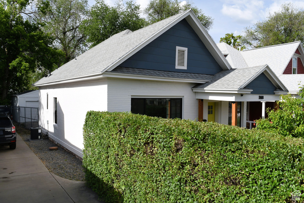 View of front of home with a shingled roof and cooling unit