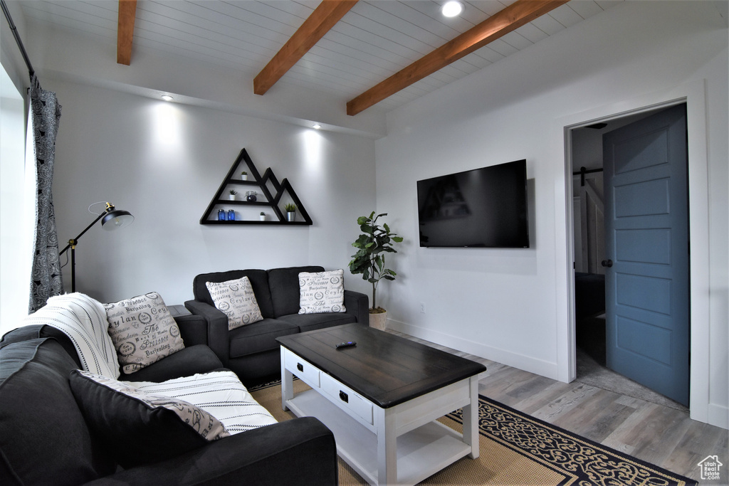 Living room with light wood-style floors, wood ceiling with exposed beams, baseboards, and recessed lighting
