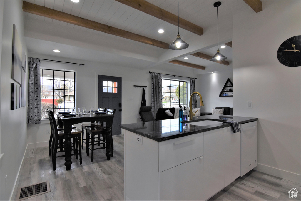 Kitchen featuring a sink, light wood-style floors, baseboards, dishwasher, and beam ceiling