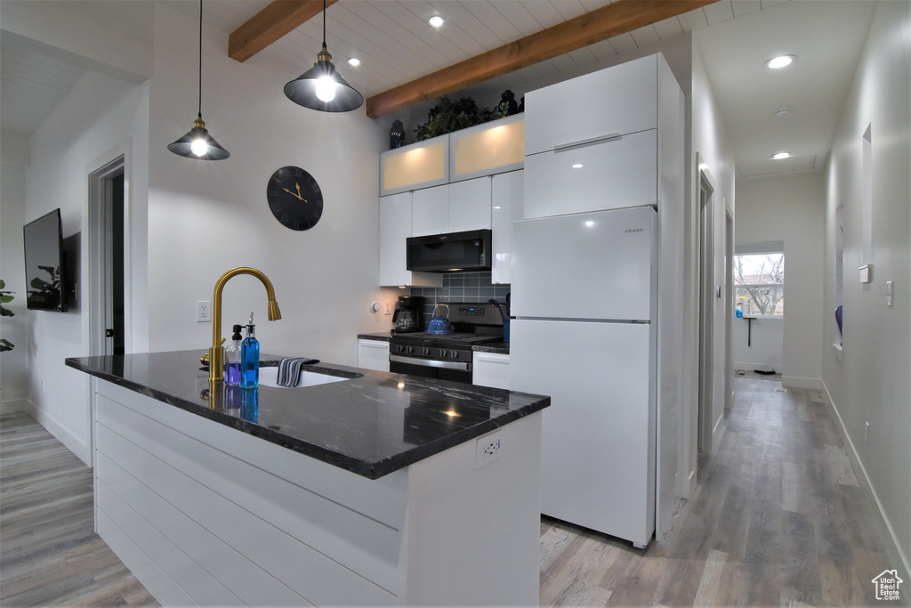 Kitchen with black appliances, a sink, beam ceiling, white cabinetry, and light wood-style floors
