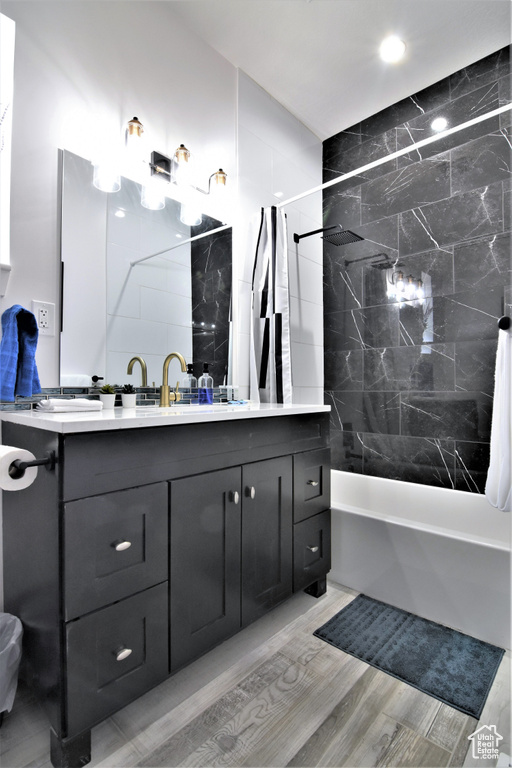 Bathroom featuring shower / tub combo with curtain, double vanity, recessed lighting, and wood finished floors