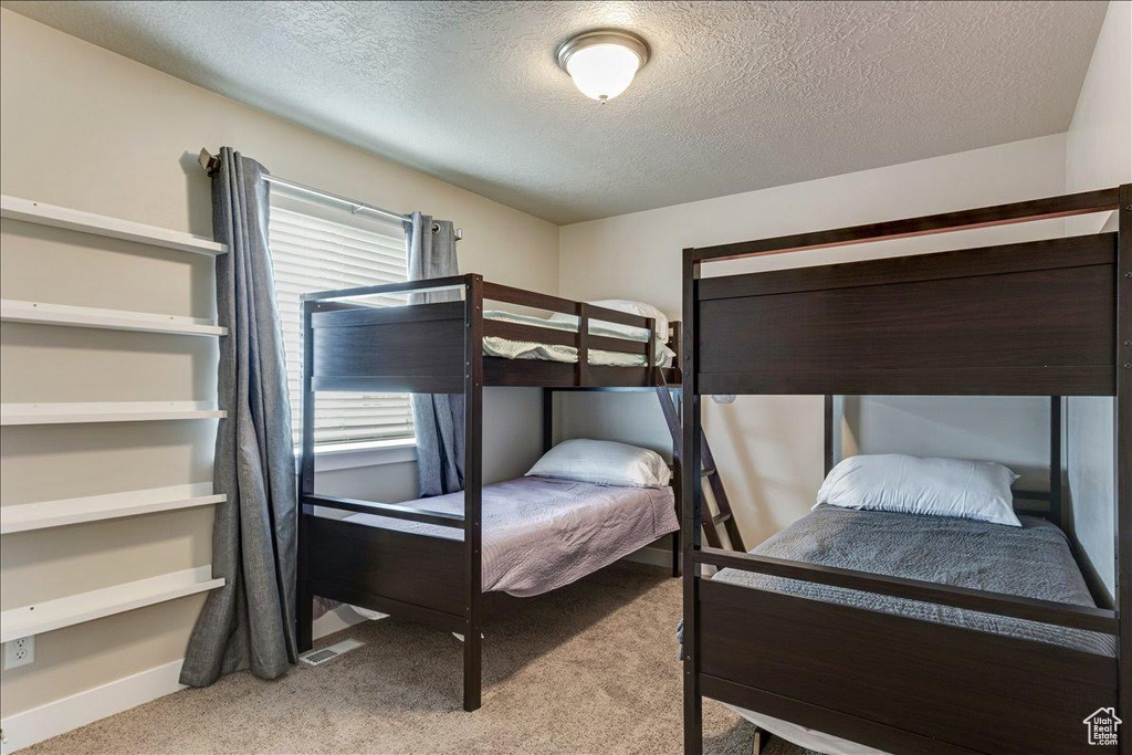 Carpeted bedroom featuring a textured ceiling and baseboards