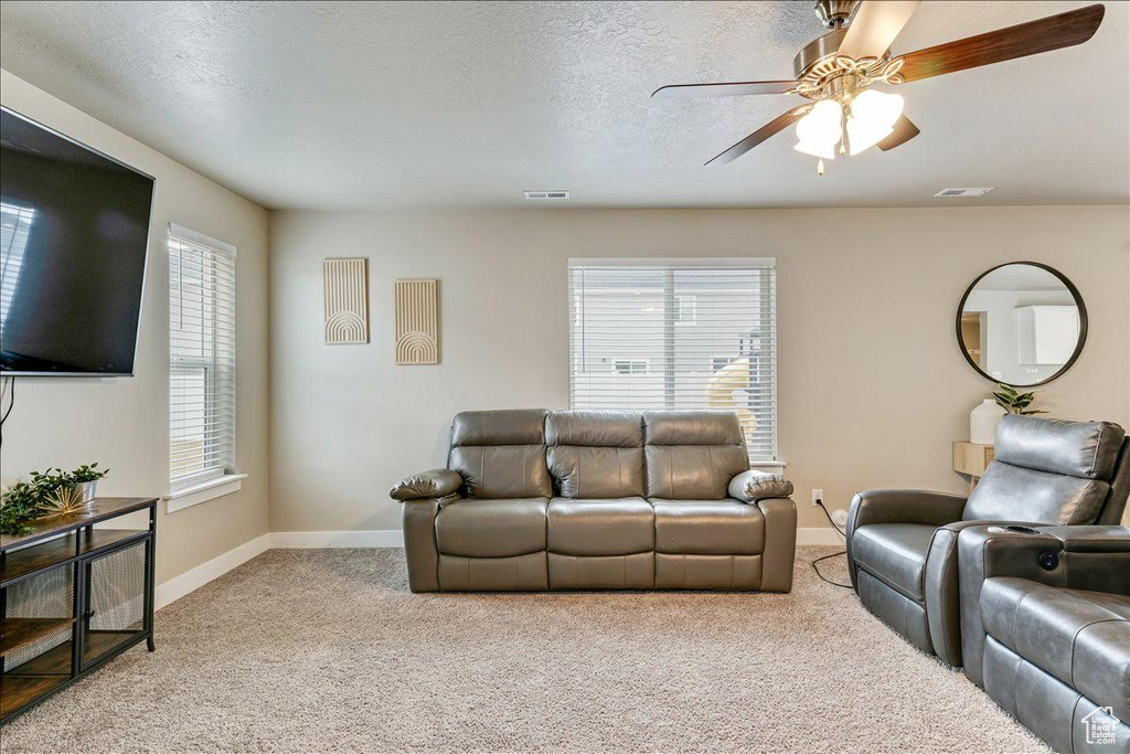 Living room with light colored carpet, a ceiling fan, and baseboards