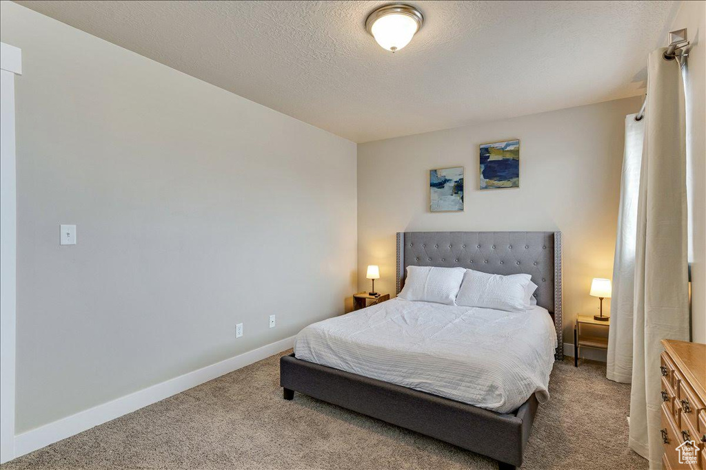 Carpeted bedroom featuring baseboards and a textured ceiling