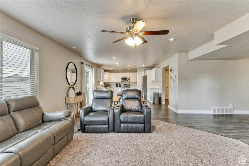 Living room featuring ceiling fan, baseboards, dark wood-type flooring, and recessed lighting
