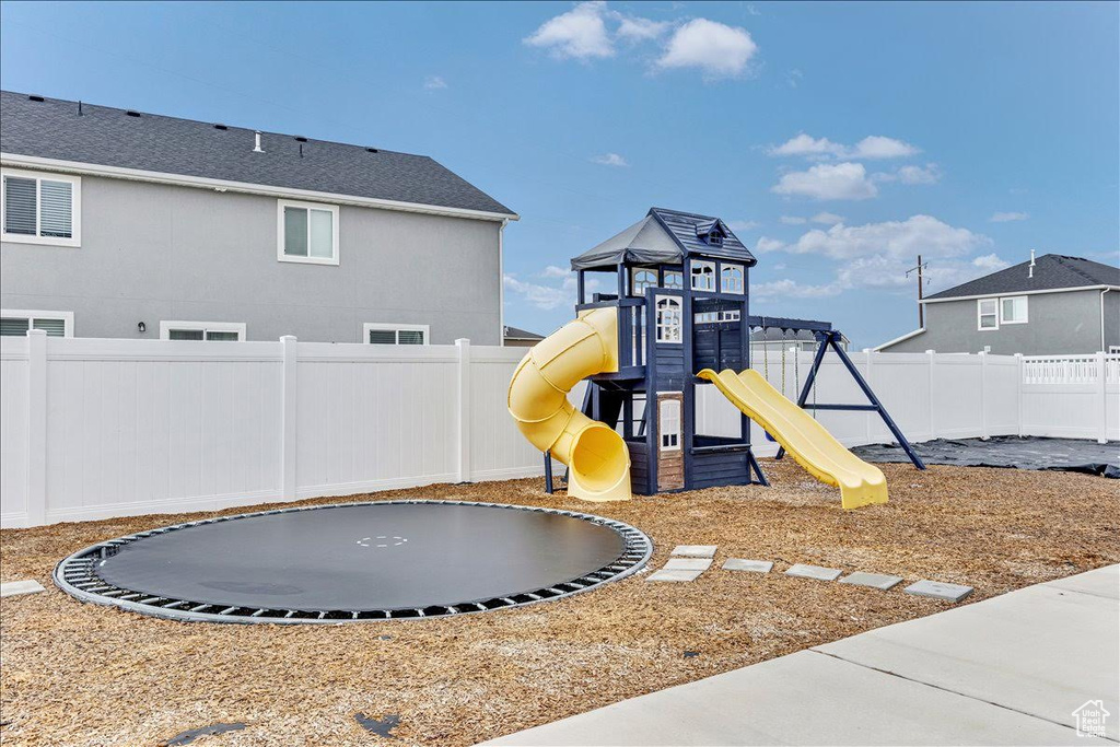 View of play area featuring a trampoline and a fenced backyard