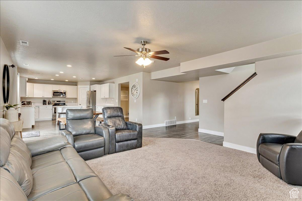 Living room with baseboards, ceiling fan, recessed lighting, carpet flooring, and wood finished floors