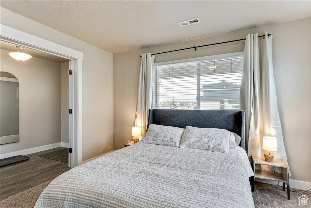 Bedroom with arched walkways, baseboards, and wood finished floors