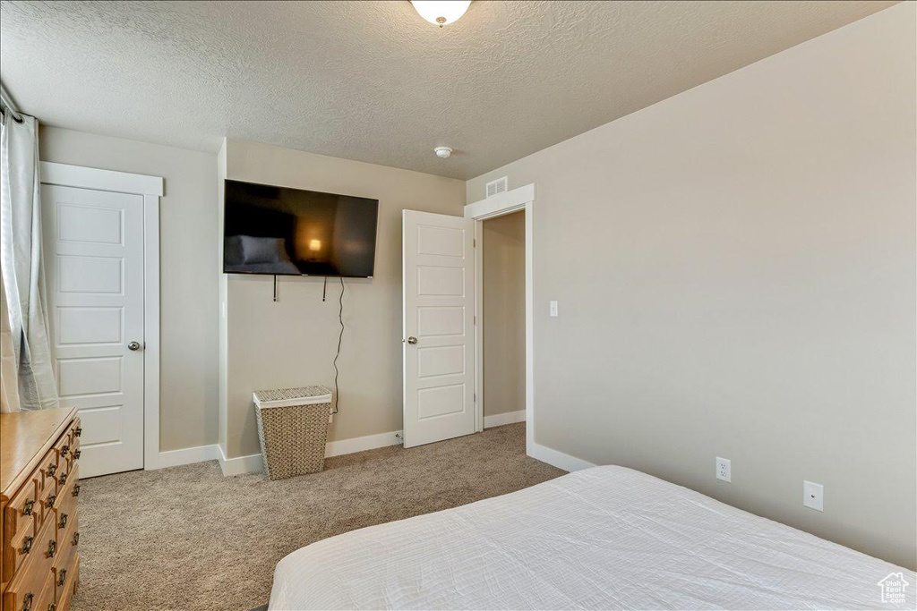 Carpeted bedroom featuring baseboards and a textured ceiling