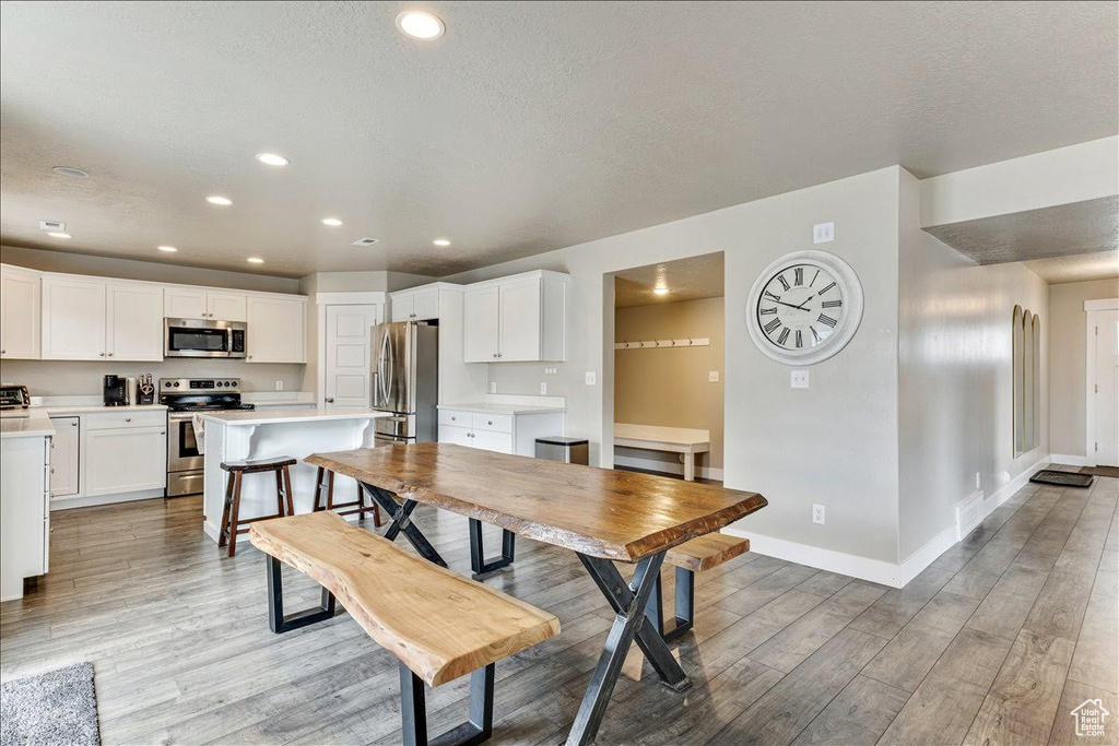Dining space featuring light wood-style flooring, baseboards, recessed lighting, and a textured ceiling