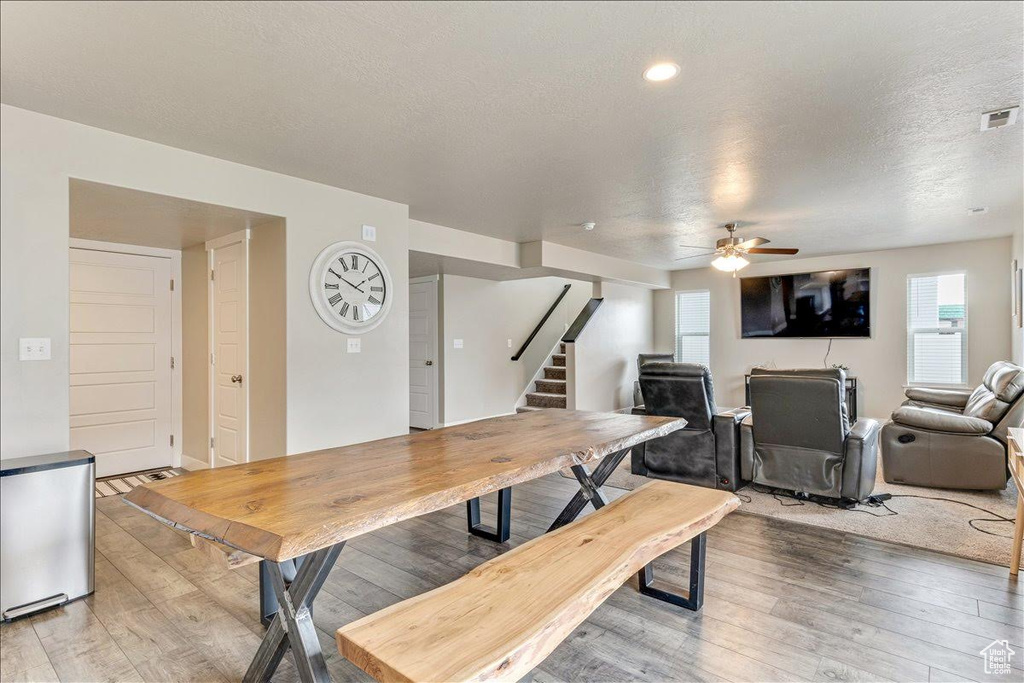 Dining room with light wood finished floors, stairs, ceiling fan, and a textured ceiling