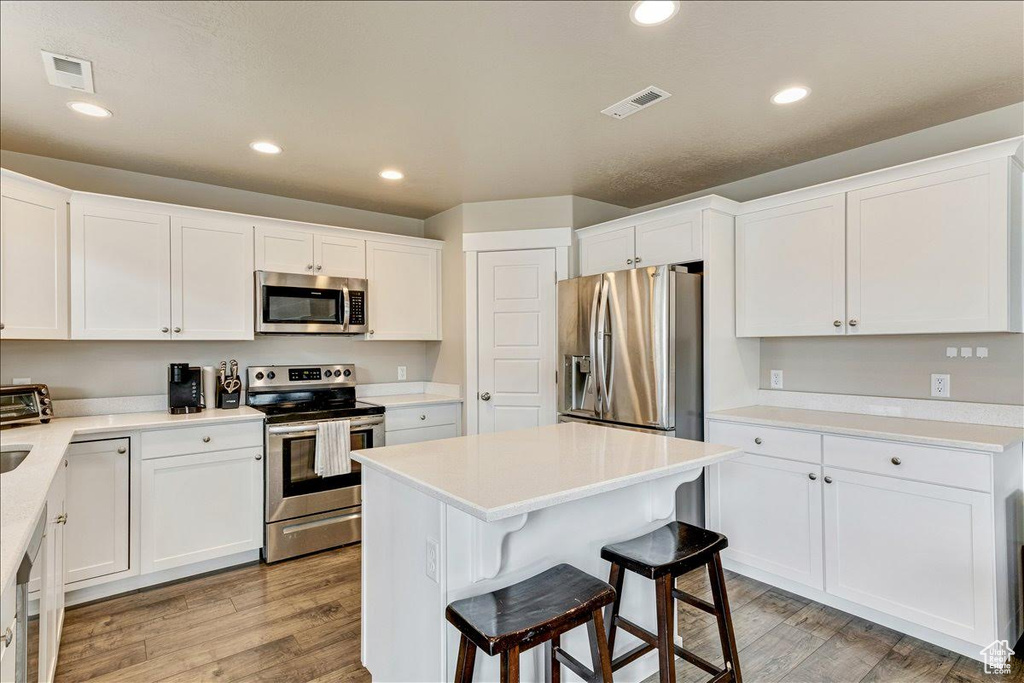 Kitchen featuring appliances with stainless steel finishes, light wood-style flooring, white cabinetry, and recessed lighting