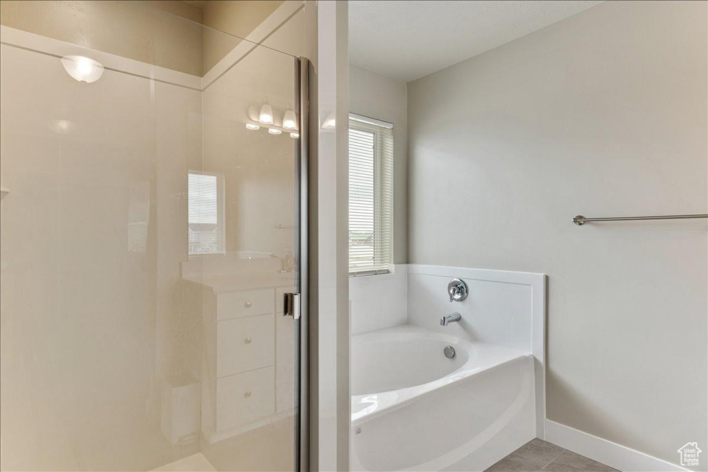 Full bathroom with a garden tub, a shower stall, tile patterned flooring, and baseboards