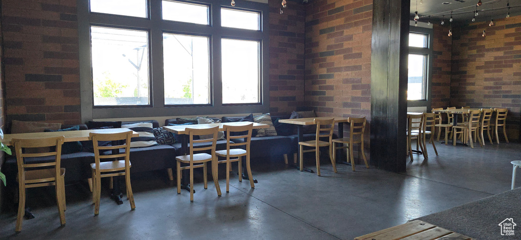 Dining space featuring finished concrete floors, brick wall, and track lighting
