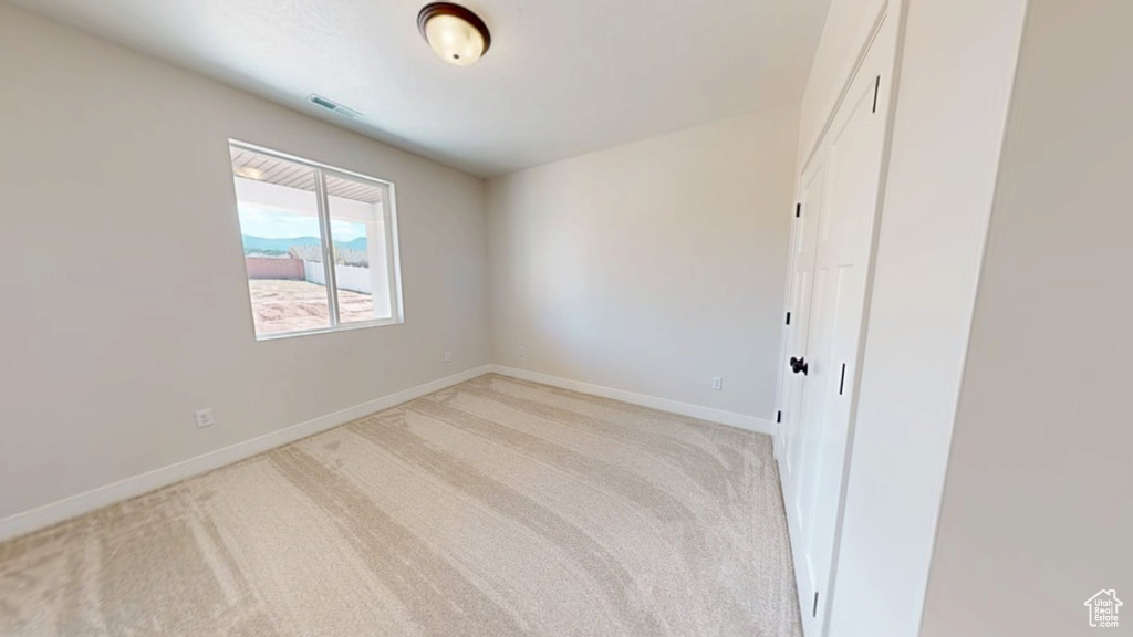 Empty room with light carpet and baseboards