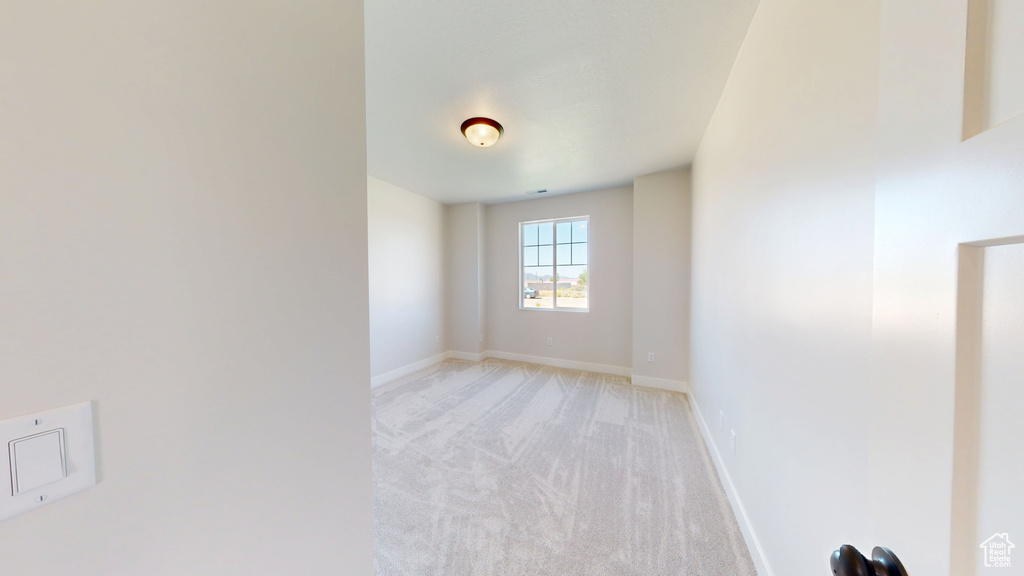 Spare room featuring light colored carpet and baseboards