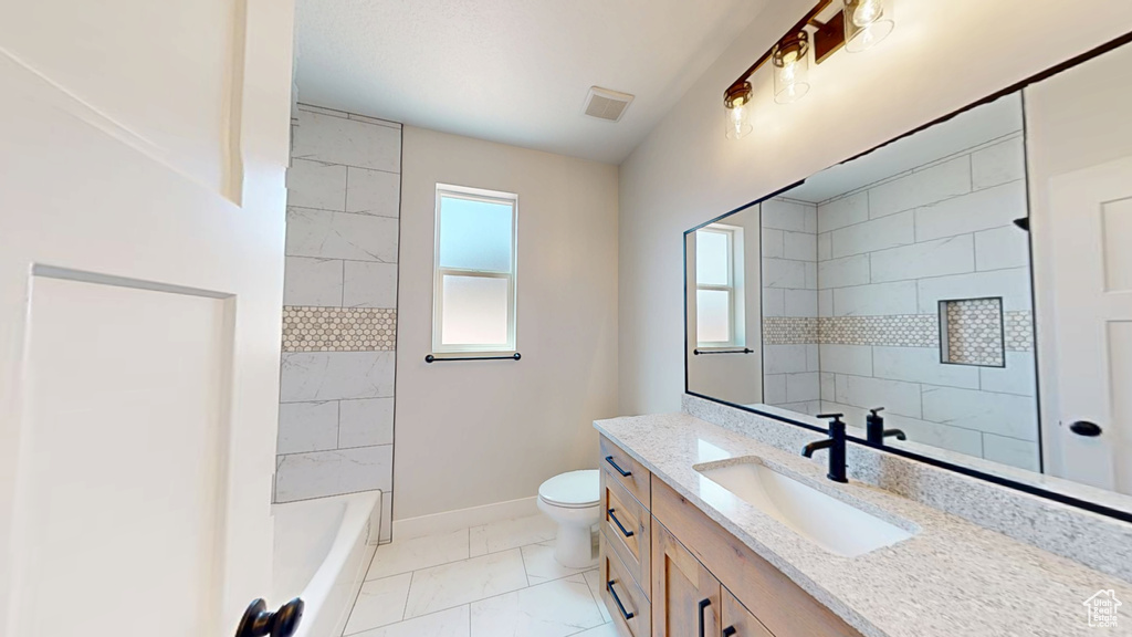 Bathroom with vanity, baseboards, toilet, marble finish flooring, and shower / washtub combination