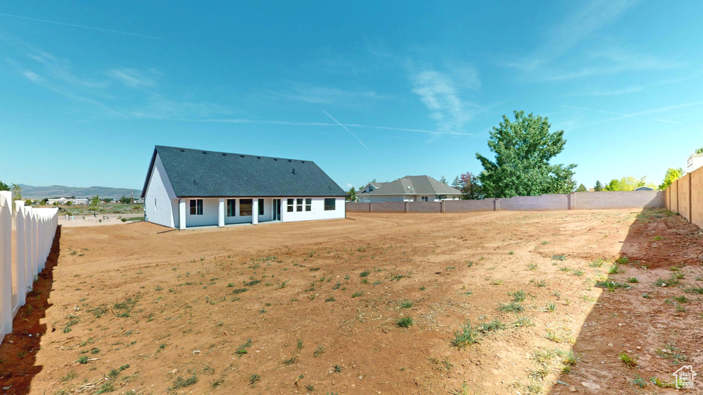 Back of house with a fenced backyard and a shingled roof