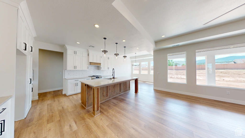 Kitchen featuring a sink, light countertops, light wood finished floors, recessed lighting, and decorative backsplash