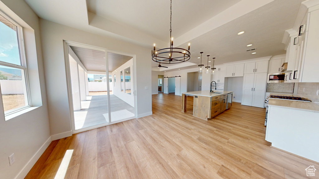 Kitchen with a sink, a chandelier, light wood-type flooring, light countertops, and recessed lighting