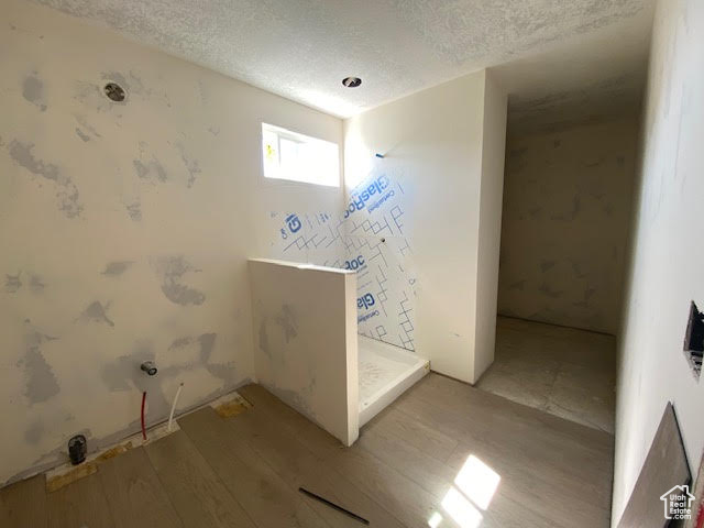 Laundry area with light wood-style flooring and a textured ceiling