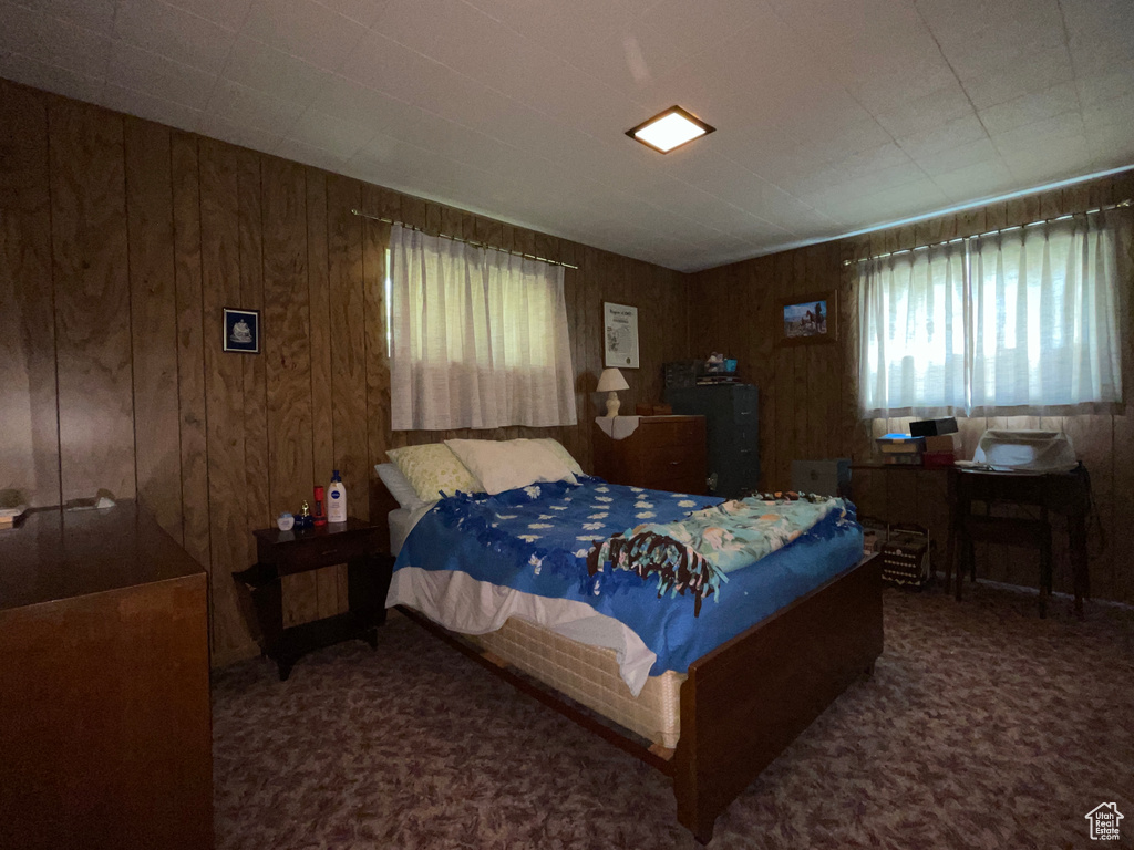 Carpeted bedroom with multiple windows and wooden walls