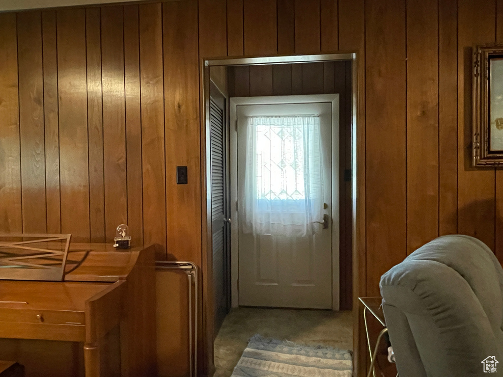 Doorway to outside featuring wood walls and light colored carpet