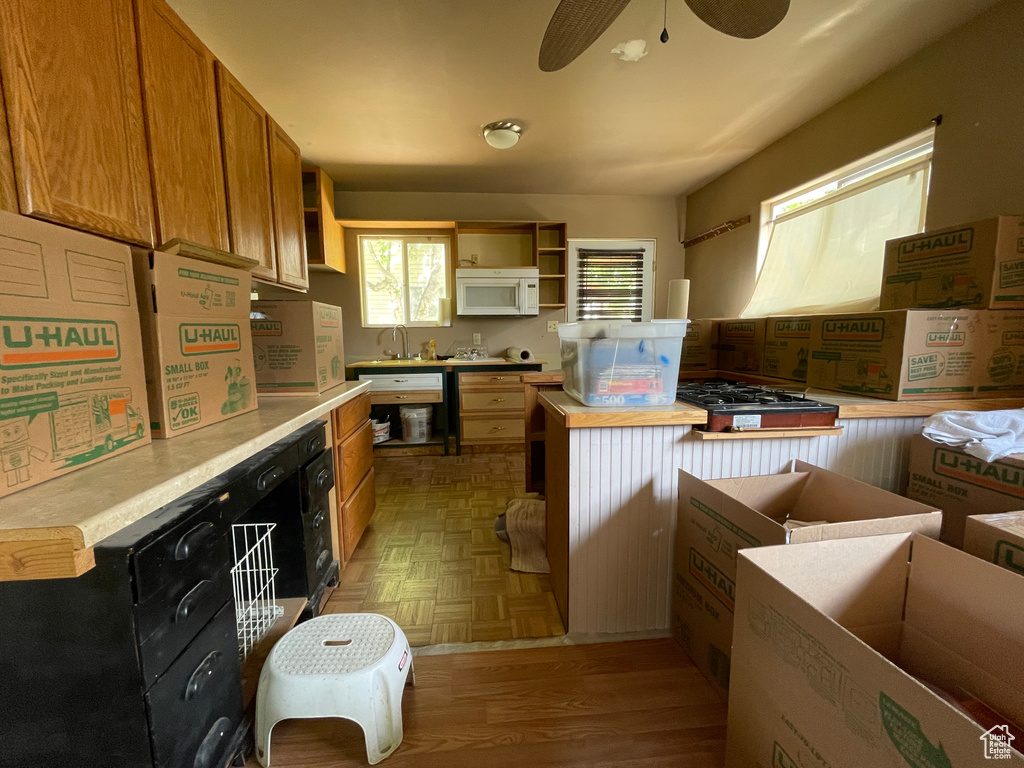 Kitchen with white microwave, light countertops, open shelves, and a ceiling fan