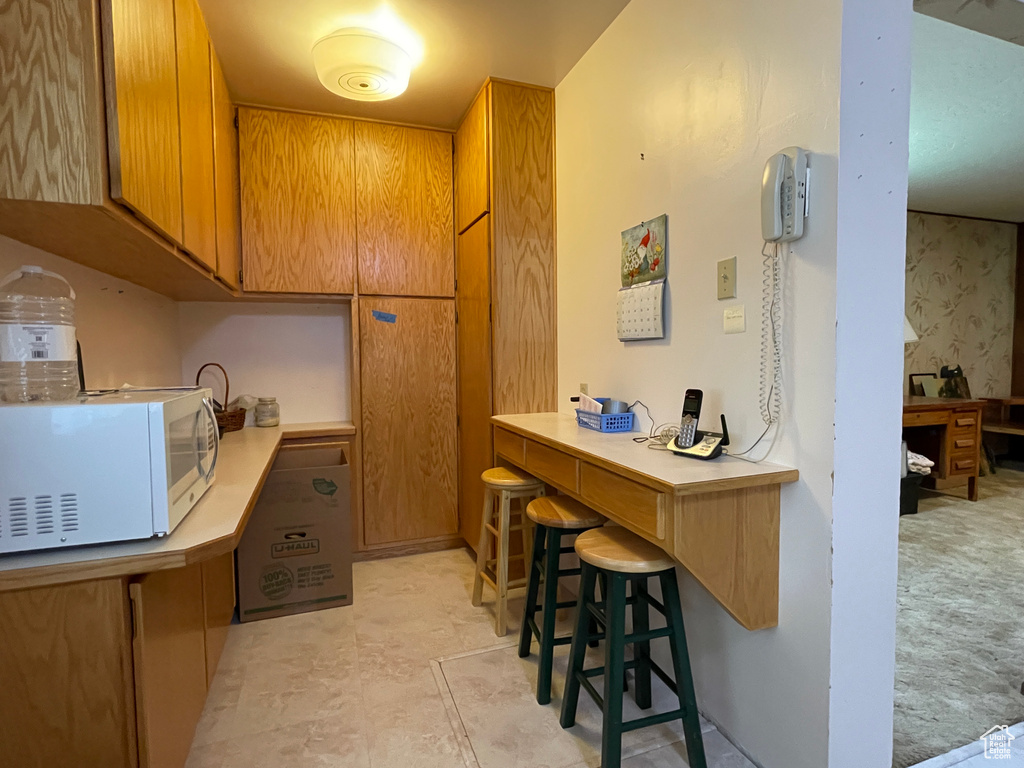 Kitchen with white microwave, light countertops, and brown cabinets
